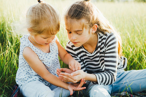  two children looking at a moth that they have caught